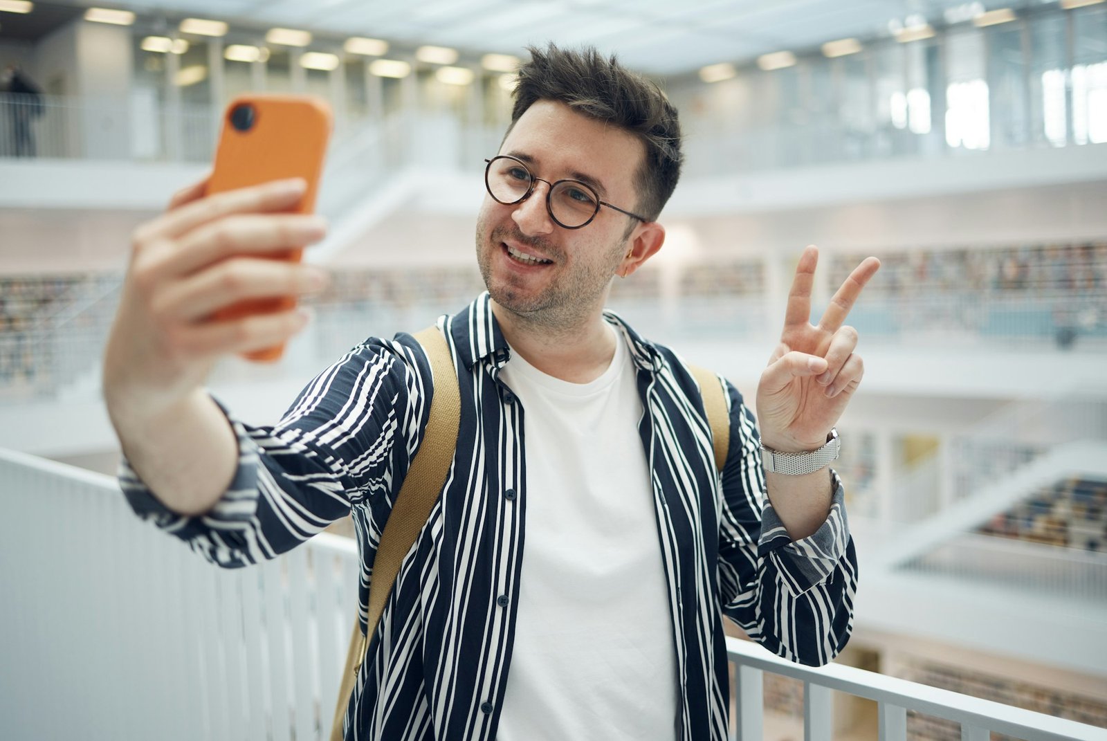 College student, man and library selfie at campus with phone, peace hand and smile on social media.